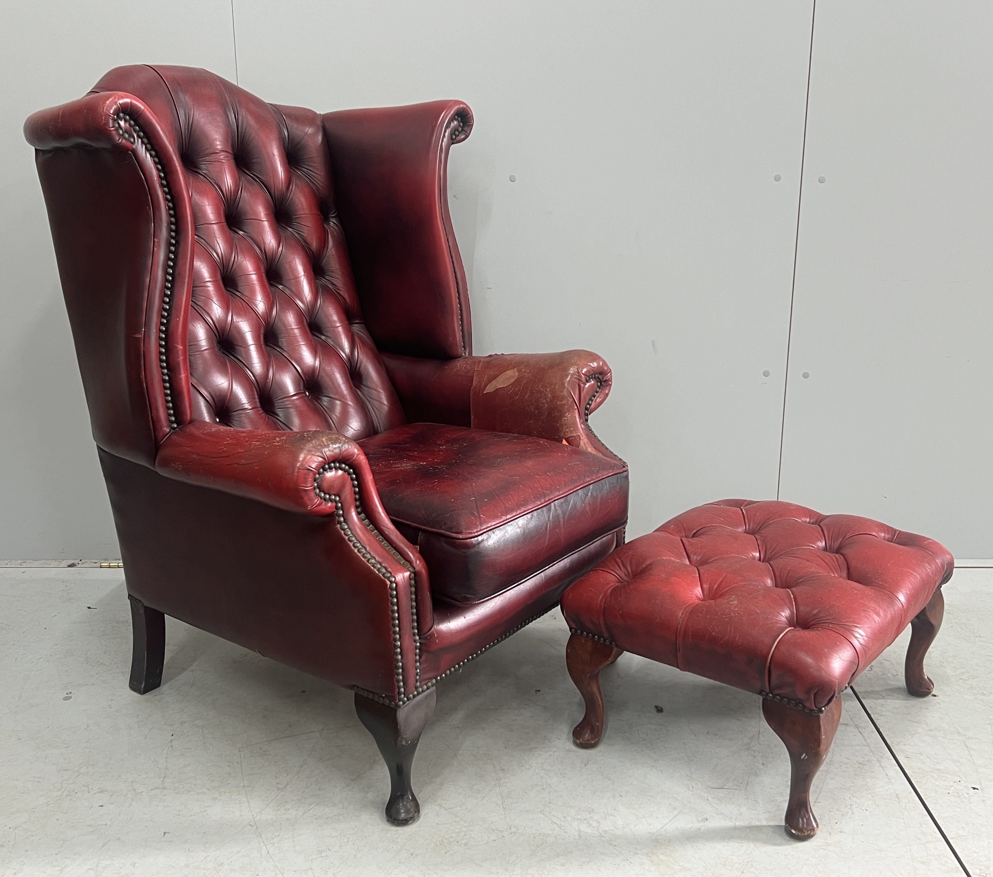 A Victorian style leather armchair, width 82cm, depth 80cm, height 110cm and footstool